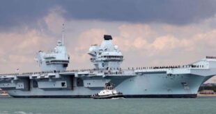 A photo of the HMS Prince of Wales anchored near harbor. 