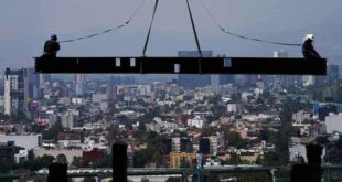 Construction workers ride on a beam hanging from a crane at the construction site of a residential high-rise building in Mexico City on June 17, 2022. Mexico’s Senate approved a bill on Oct. 26, 2022, to eliminate daylight savings time.